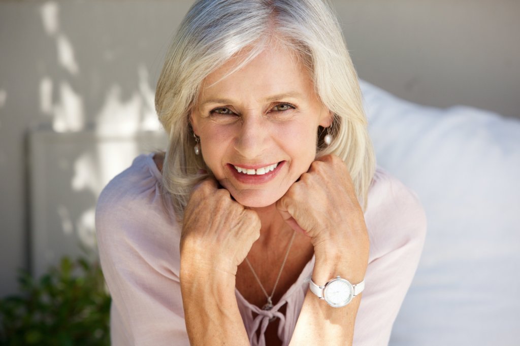 smiling older woman with hand in hands outside