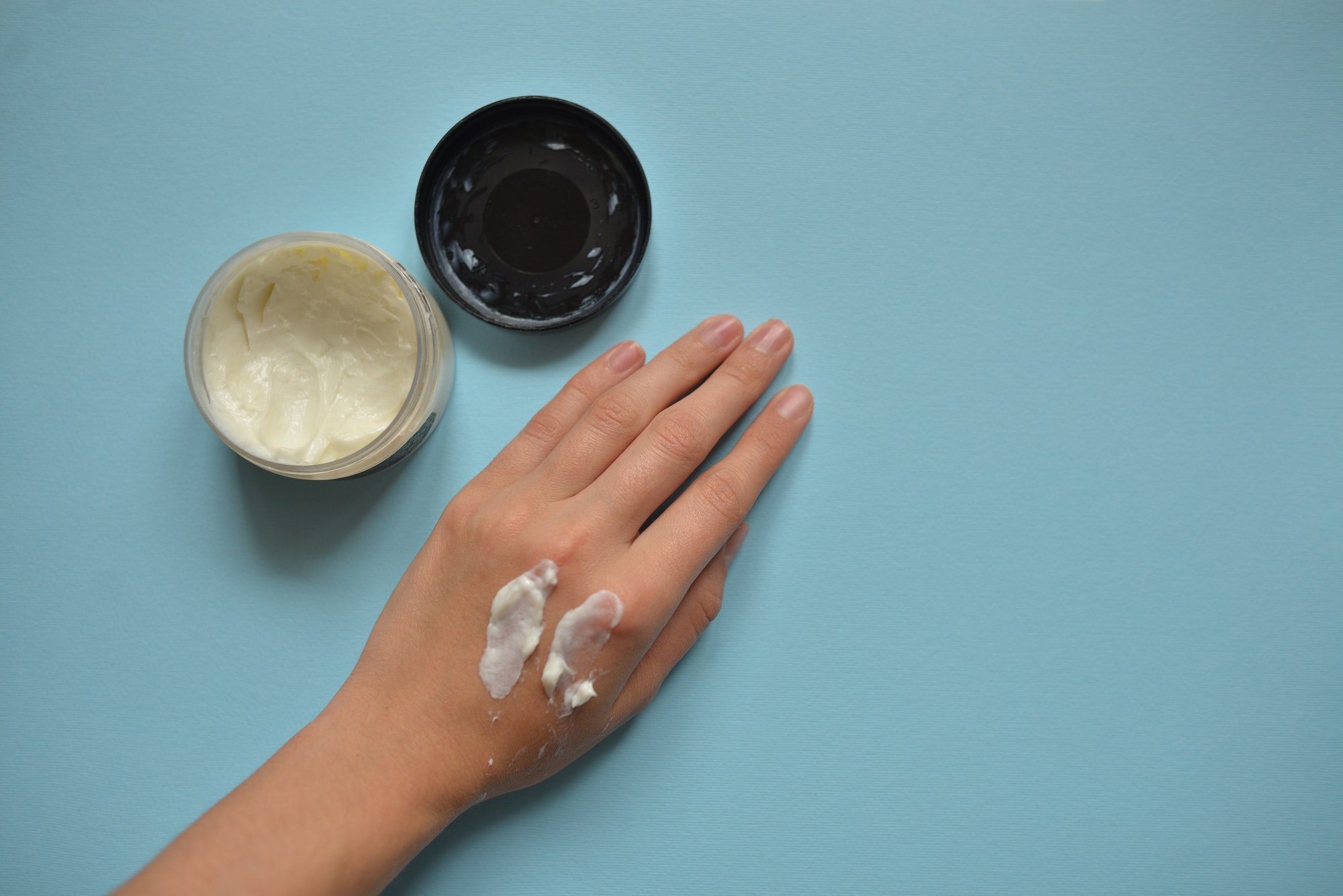 Hand with cream on it with blue background. Dry skin need care especially in winter.