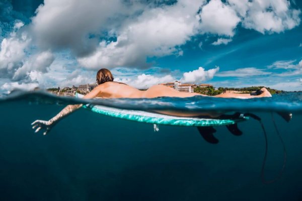 Surf girl floats on surfboard. Naked woman during surfing. Surfer and ocean