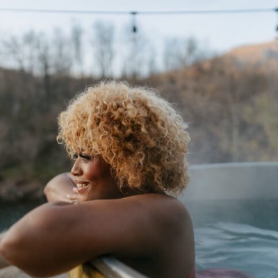 Photo of a beautiful African American woman soaking in a hot tub hot tub, while vacationing in a rental property on a remote location