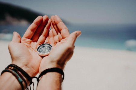 man-39-s-hand-holding-compass-against-the-backdrop-of-beach-and-sea-the-concept-of-travel-summer.jpg