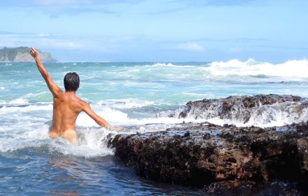 A naked man in the sea is raising his fist, striking a victory pose.
You can feel yourself to be a part of nature with your whole skin.