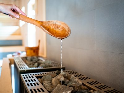 Pouring water on hot stone into heater in sauna